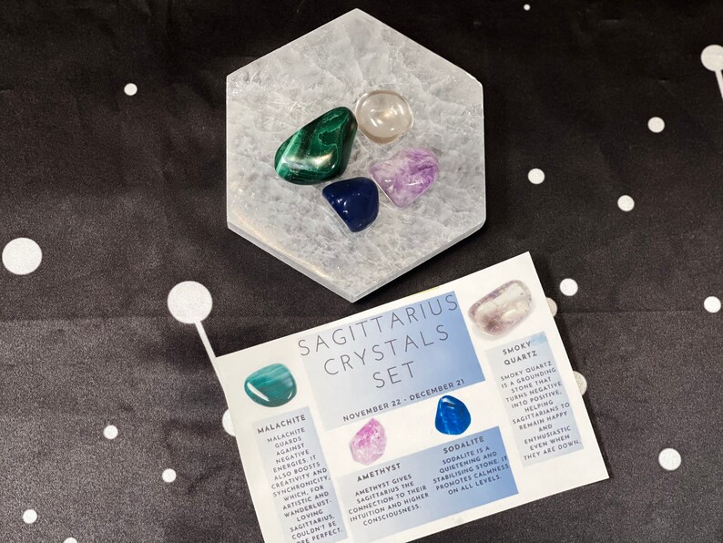 May include: A set of crystals for the Sagittarius zodiac sign. The set includes smoky quartz, amethyst, sodalite, and malachite crystals. The crystals are arranged on a white hexagonal crystal plate. The crystals are labeled with their names and their astrological meanings.