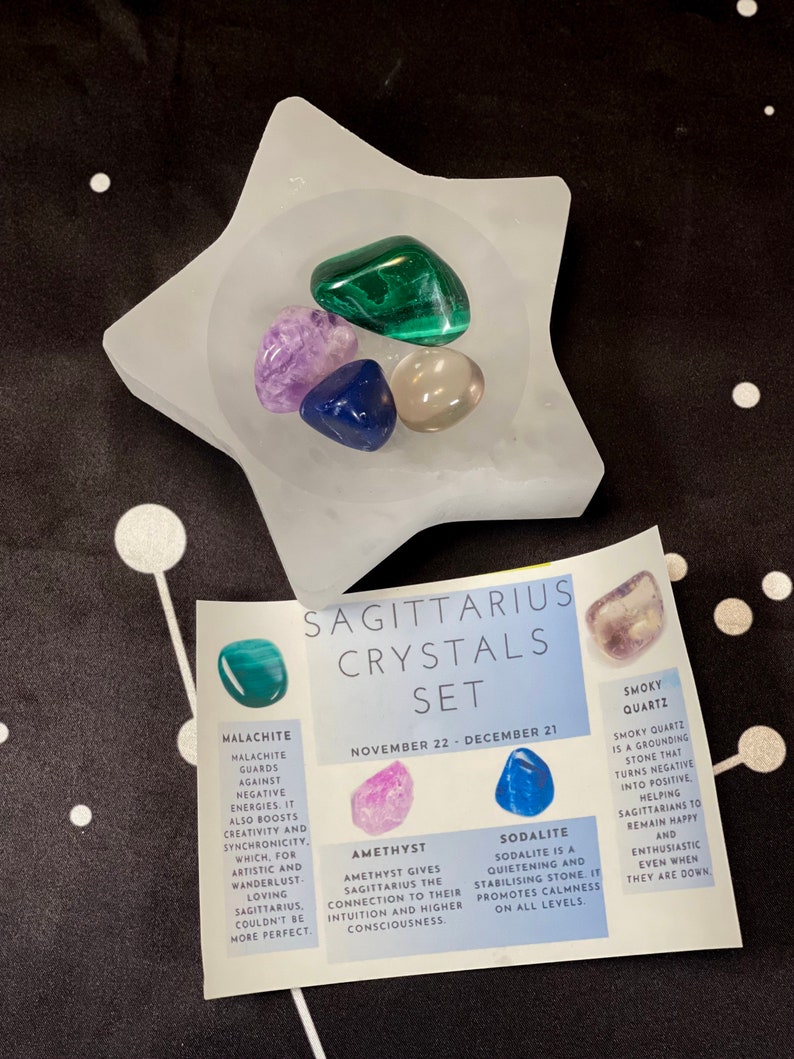 May include: A set of crystals for the zodiac sign Sagittarius, November 22 - December 21. The set includes amethyst, sodalite, smoky quartz, and malachite crystals in a white star-shaped dish. The crystals are described with their properties and how they benefit Sagittarius.