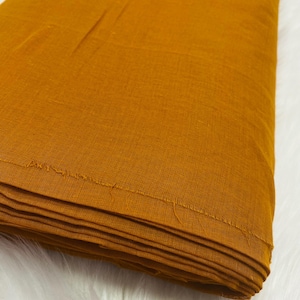 May include: A folded piece of mustard yellow fabric. The fabric has a smooth, slightly textured surface.