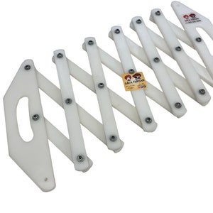 May include: White plastic expandable safety barrier with a handle and multiple interlocking sections. The barrier is designed to be used as a safety device to block traffic or pedestrians.
