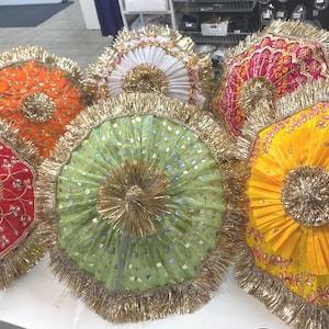 May include: A selection of vibrant, circular decorative pieces with gold fringe. The items display a range of colours, such as red, orange, green, and yellow, with detailed embroidered patterns and central adornments.