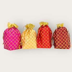May include: Four decorative drawstring bags with gold and red patterned fabric. The bags are lined up in a row from left to right: pink, beige, red, and burgundy.