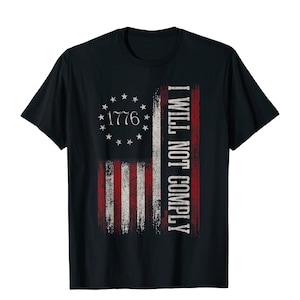 May include: Black t-shirt featuring a distressed American flag design with the text "1776" inside a circle of stars. The right side of the flag has the words "I WILL NOT COMPLY" in white. The shirt is a classic crew neck style.