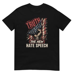 Puede incluir: Una camiseta negra de manga corta con un estampado gráfico de una mano sosteniendo una bandera estadounidense doblada sobre un fondo de bandera desgastada. El texto TRUTH está impreso arriba y THE NEW HATE SPEECH en blanco debajo.