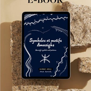 以下が含まれることがあります： 青い背景と白いテキストでデジタル電子書籍の表紙。タイトルは「Symboles et motifs Amazighs」で、サブタイトルは「Amazigh symbols and patterns」。表紙には白いシンボルと「BERBERE WOMAN」と「Sarah handele」のテキストも含まれています。