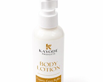 May include: A white body lotion bottle with a pump dispenser. The label features the brand name "KAYODE PRODUCTS" and the words "BODY LOTION" in gold lettering. The label also states "Organic Cocoa Butter & Coconut Oil" and the volume is 100ml.