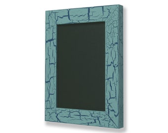 May include: A rectangular chalkboard with a distressed teal frame. The frame has a cracked paint effect, with darker blue accents in the cracks. The chalkboard surface is black.