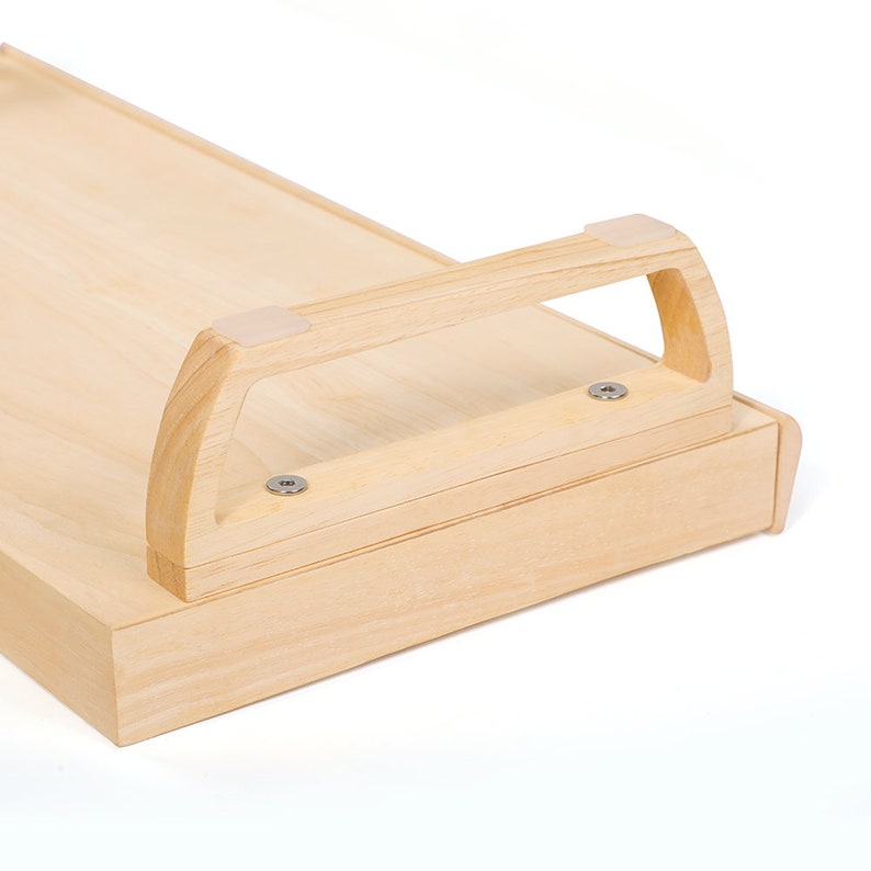 May include: A light wood tray with a handle on the side. The tray has a smooth surface and is made of natural wood. The handle is made of the same wood and has a simple design.