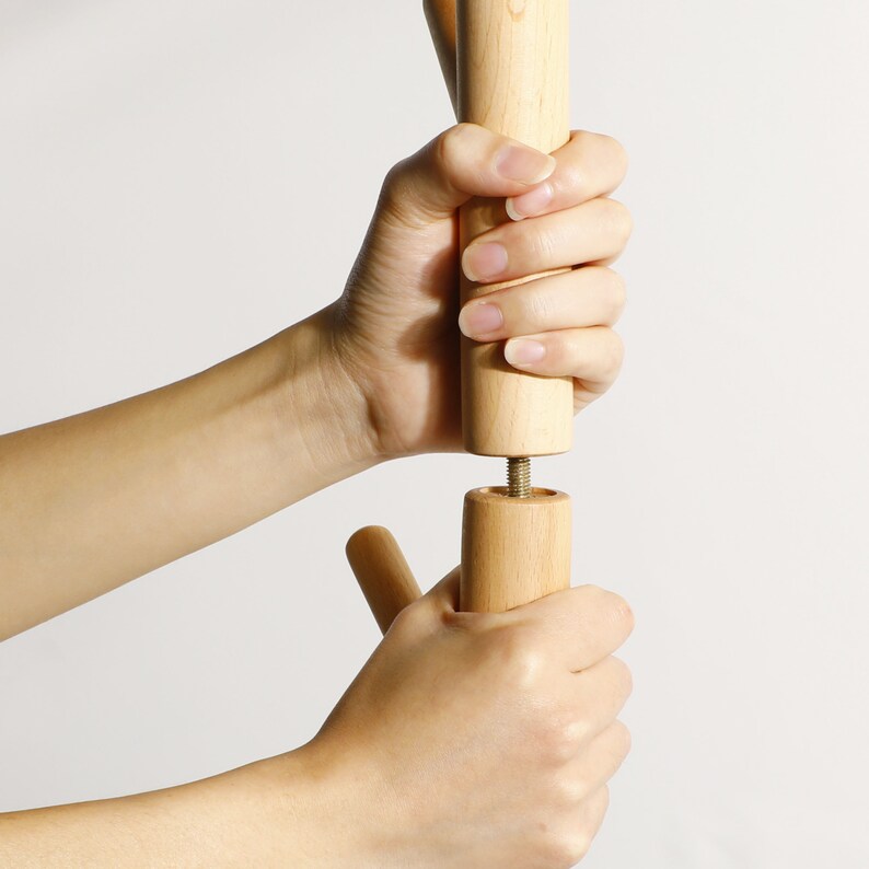 Puede incluir: Dos manos ensamblando un soporte de madera atornillando dos piezas de madera juntas.