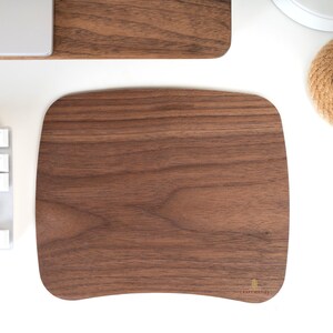 May include: A dark brown, curved, wooden mouse pad with a slightly raised edge. The mouse pad has a natural wood grain pattern and the text "CRAFT KITTIES" is printed in the bottom right corner.
