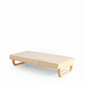 May include: A light wood coffee table with two drawers and curved legs. The table is made of natural wood and has a simple, modern design.