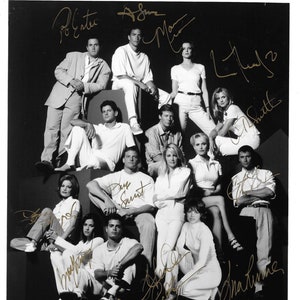 Puede incluir: Foto en blanco y negro del elenco de la serie de televisión Melrose Place. Los miembros del elenco están todos de pie en grupo y sonriendo. La foto está firmada por todos los miembros del elenco. La foto está subtitulada "Melrose Place".