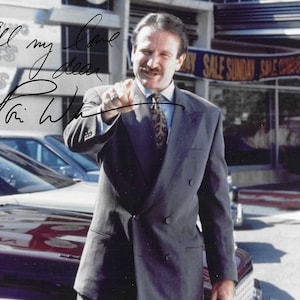 Könnte beinhalten: Ein Schwarz-Weiß-Foto von Robin Williams in einem dunklen zweireihigen Anzug, einem hellen Hemd und einer gemusterten Krawatte. Das Bild enthält eine handschriftliche Signatur in schwarzer Tinte und die Aufschrift All my love dear Robin Williams.