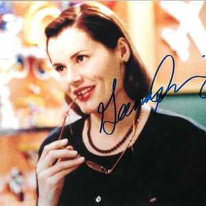 Puede incluir: Una mujer con el pelo castaño corto lleva una camisa negra y un collar. Está sosteniendo un par de gafas en su mano derecha y mirando hacia un lado. El fondo está desenfocado y presenta un diseño abstracto de colores.