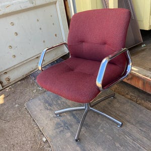 Puede incluir: Silla de oficina burdeos con asiento y respaldo de tela texturizada. La silla tiene reposabrazos cromados y una base de cinco estrellas. Dise&ntilde;ada para la comodidad y el apoyo, adecuada para el hogar o la oficina.