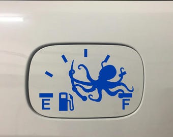 May include: Blue octopus fuel gauge sticker on a white car. The sticker features a stylized octopus design with the letters "E" and "F" indicating empty and full, and a fuel pump icon. The sticker is applied to the fuel door.