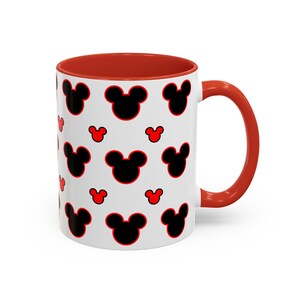 May include: A white ceramic mug featuring a repeating pattern of black Mickey Mouse head silhouettes outlined in red. The mug has a solid red handle and a red interior rim, providing a consistent color scheme throughout the design.