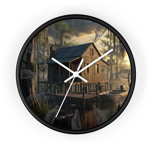 May include: Black-framed wall clock featuring a detailed illustration of a wooden cabin on a lake, with a boat docked at a pier. The scene includes trees, water, and a cloudy sky, creating a rustic, nature-inspired design.
