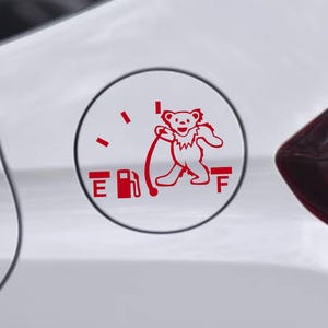 May include: Red decal on a white car featuring a dancing bear graphic. The decal is designed to look like a fuel gauge, with the bear holding the fuel pump nozzle. The gauge reads "E" and "F".