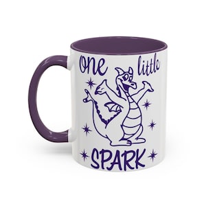 May include: White ceramic mug with a purple interior and handle. The mug features a purple illustration of a cartoon dragon with the text "one little SPARK" in purple. The design includes stars around the dragon.