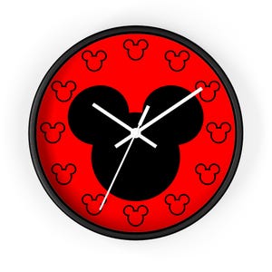 May include: A round wall clock with a black frame and a vibrant red face. The center features a large black silhouette of a mouse head. The background is decorated with a repeating pattern of smaller black mouse head outlines. Three white hands.