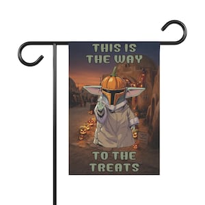 May include: A rectangular garden flag featuring a cartoon character with large ears wearing a helmet topped with a pumpkin. The text reads THIS IS THE WAY TO THE TREATS. The scene depicts a desert village at sunset with glowing jack-o'-lanterns.