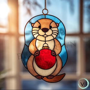 Pode incluir: Vitral de uma lontra segurando um enfeite vermelho, com um esquema de cores azul e marrom. A lontra tem um corpo marrom claro, um rosto branco e um nariz preto. O enfeite é redondo e tem um acabamento brilhante. A peça foi projetada para pendurar.