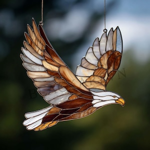 May include: A stained glass eagle in flight, with brown, white, and gold hues. The wings are outstretched, displaying a detailed mosaic pattern. A decorative item, ideal for adding nature-themed art to a room or garden.
