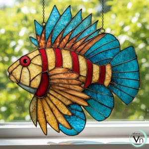 Peut inclure: Poisson en vitrail aux couleurs vives. Le corps est jaune avec des rayures rouges, les nageoires bleues et un œil rouge. Suspendu par une chaîne, idéal pour la décoration de fenêtre.