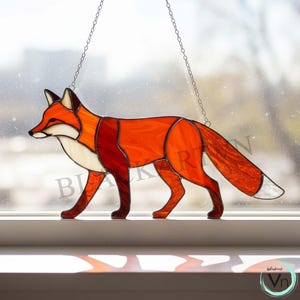 May include: Stained glass fox suncatcher in shades of orange, red, and white, with a chain for hanging. The fox is depicted in a walking pose, with detailed glasswork creating a textured appearance. A decorative piece for windows or walls.