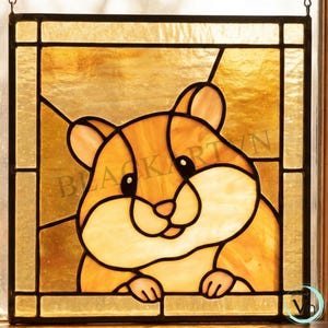 May include: Stained glass panel featuring a cartoon hamster in shades of brown, tan, and cream. The hamster is peeking over a ledge. The text "BLACK KART VN" is visible. The panel is framed with a dark border.