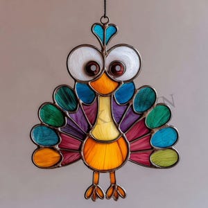 May include: A colorful stained glass peacock with large, expressive eyes and a heart-shaped crest. The peacock features a vibrant array of colors, including blue, green, purple, and orange, with a detailed metal frame. This decorative piece is designed to hang.