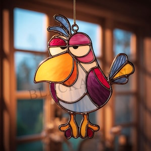 May include: Stained glass bird ornament with a whimsical design. The bird features a large orange beak, purple body, and blue accents. The ornament is suspended by a gold chain and is suitable for hanging in a window or as a decorative piece.