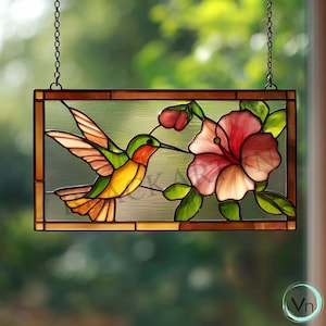 Peut inclure: Panneau de fenêtre en vitrail représentant un colibri en vol approchant une fleur d'hibiscus rose. L'oiseau a un plumage vert, jaune, orange et rouge. Le panneau rectangulaire a une bordure marron et est suspendu par une chaîne.