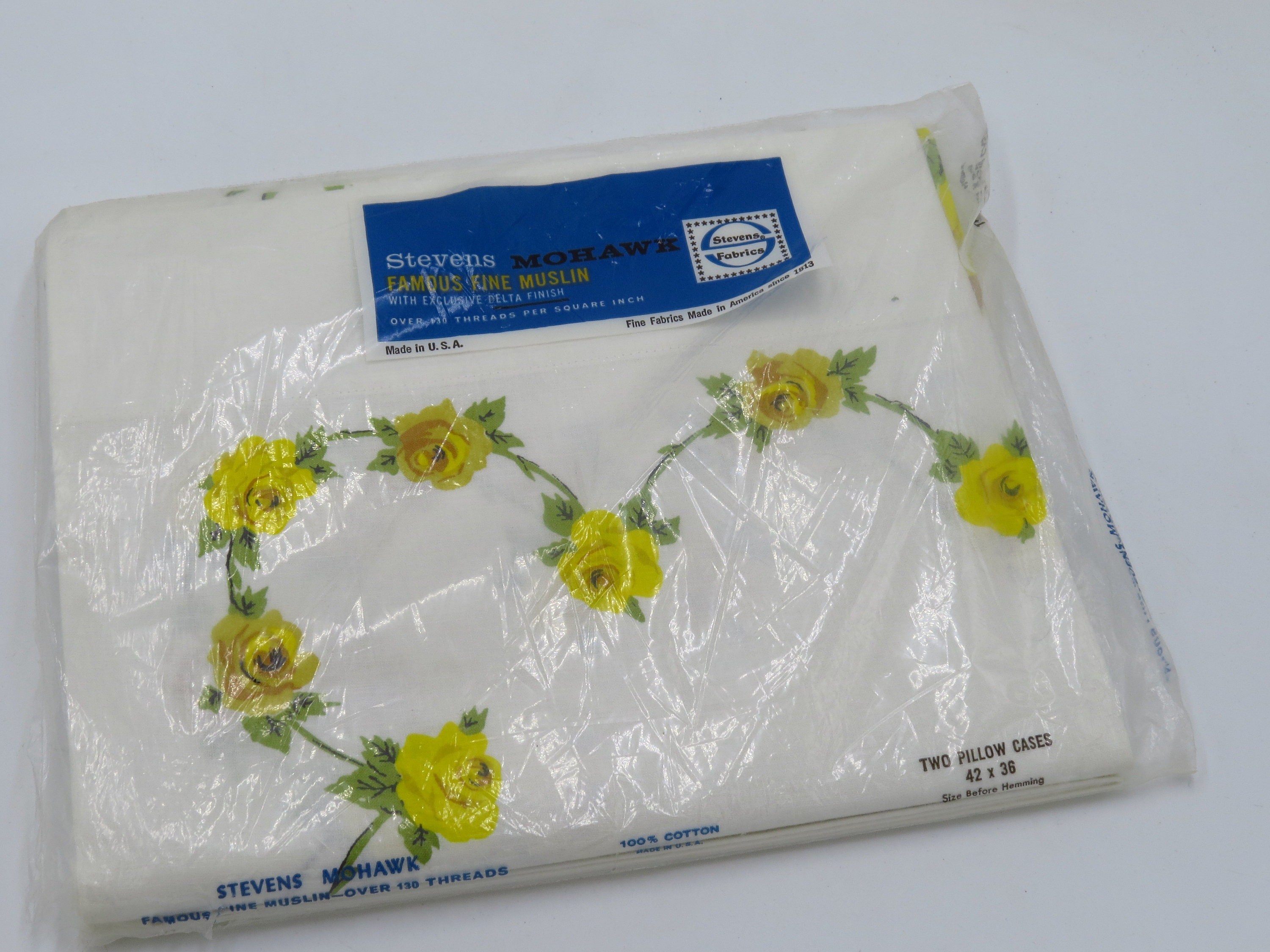 May include: Two white pillowcases with yellow rose pattern. The pillowcases are packaged in plastic and labeled "Stevens Mohawk Famous Fine Muslin Over 100 Threads 100% Cotton" and "Two Pillow Cases 42 x 38".