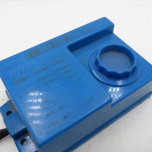 May include: Blue plastic Life-Like model train power transformer with a knob to adjust the voltage. The transformer has a UL safety listing and the text "HO/H0m POWER TRANSFORMER 120V AC INPUT 12V DC OUTPUT OPEN CIRCUIT VOLTAGE 18V MAX"