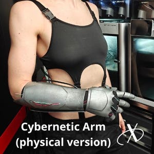 Puede incluir: Se muestra un brazo cibernético plateado y negro, con el texto "Cybernetic Arm (versión física)". El brazo está unido a una persona que lleva una parte superior negra. El fondo presenta impresoras 3D.