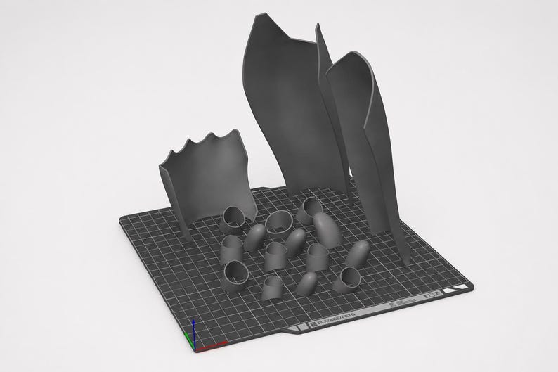 May include: A collection of dark gray 3D printed components arranged on a black grid build plate. The set includes three large, curved, shield-like panels and several smaller, hollow, cylindrical and rounded pieces with open ends.