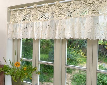 Cortina de crochê bege com amarração em renda estilo shabby chic, ideal para decoração de janelas em casas de campo e cozinhas rústicas. Possui babados e mede 36 cm de altura.