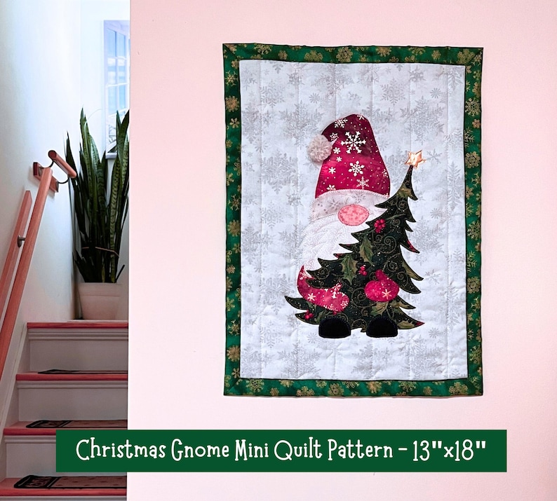 May include: A Christmas gnome mini quilt pattern with a green border and a white background featuring a gnome holding a Christmas tree. The text "Christmas Gnome Mini Quilt Pattern - 13"x18" is at the bottom of the image.