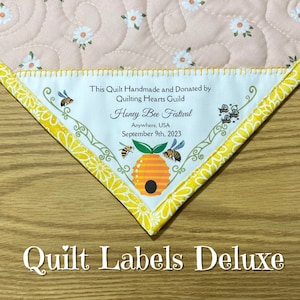 May include: A white quilt label with yellow trim and a beehive design. The label reads "This Quilt Handmade and Donated by Quilting Hearts Guild Honey Bee Festival Anywhere, USA September 9th, 2023".