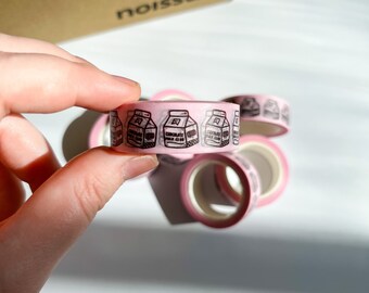 Könnte beinhalten: Rosa Washi-Tape-Rollen mit einem sich wiederholenden Muster von Milchkartons, auf denen "Chocolate Milk Club" steht.