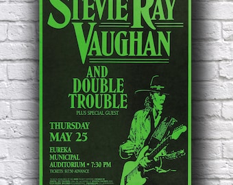 Pode incluir: Um cartaz de concerto vintage para Stevie Ray Vaughan and Double Trouble, com um esquema de cores verde e preto. O cartaz inclui a data, hora e local do concerto, juntamente com uma ilustração de um guitarrista.
