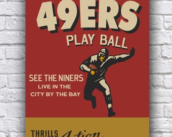 Puede incluir: Un póster de estilo vintage que anuncia un partido de fútbol americano de los San Francisco 49ers. El póster presenta un fondo rojo con el texto "WATCH THE 49ERS PLAY BALL" en letras blancas y doradas. Una imagen de dibujos animados de un jugador de fútbol americano corriendo con el balón se encuentra en el centro del póster. El texto "SEE THE NINERS LIVE IN THE CITY BY THE BAY" está debajo de la imagen. La parte inferior del póster es dorada con el texto "THRILLS Action ENTERTAINMENT!" en letras negras.