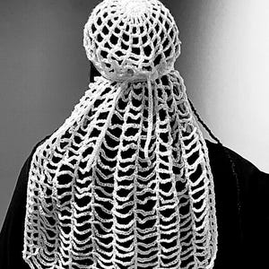 Puede incluir: Sombrero blanco de ganchillo con un velo largo y fluido. El sombrero está hecho de un diseño delicado y calado.