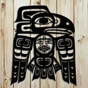 May include: A black, stylized metal wall art piece depicting a Native American totem design. The artwork features a bird-like figure with a human face at the center, and intricate cut-out details. The piece is mounted on a wooden background.