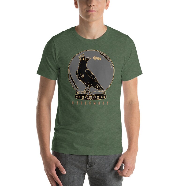 May include: A green t-shirt with a black crow wearing a crown inside a glass sphere. The crow is holding a wheat stalk in its beak. The text "NEVERMORE" is printed below the sphere.