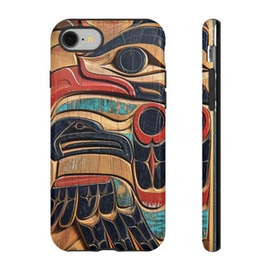 Puede incluir: Una funda para teléfono con un diseño de madera tallada de colores de un tótem nativo americano. El diseño presenta un pájaro con un pico y ojos grandes, y una combinación de colores rojo, azul y verde.