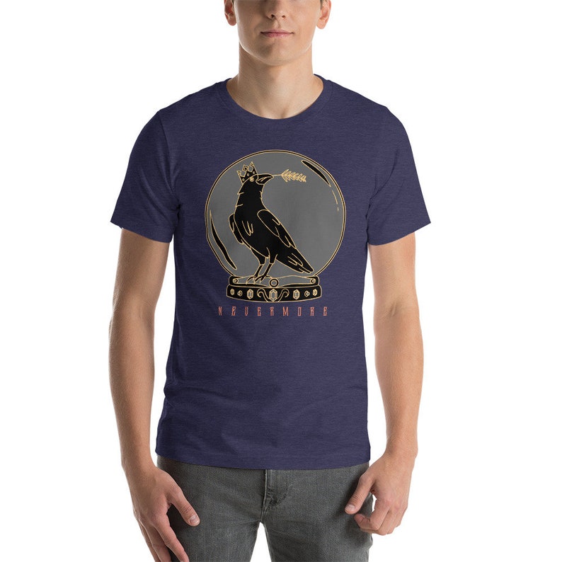 May include: A navy blue t-shirt with a graphic of a black crow wearing a crown inside a glass sphere. The crow is holding a branch in its beak. The text "NEVERMORE" is printed below the sphere.
