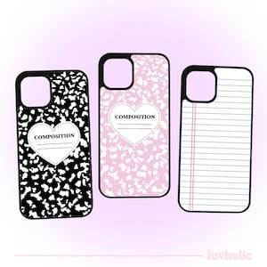 May include: Three different phone cases with a school theme. The first case is black with white splotches and a heart with the word "COMPOSITION" inside. The second case is pink with white splotches and a heart with the word "COMPOSITION" inside. The third case is white with blue lines and red lines.